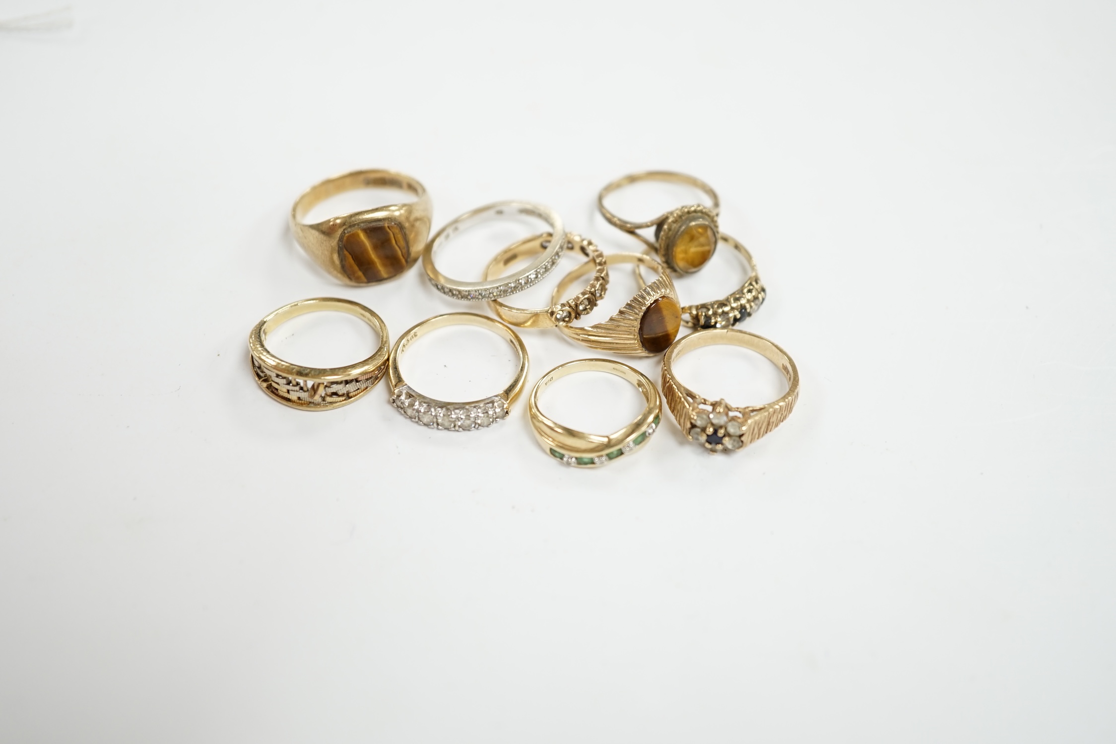 Ten assorted modern 9ct gold and mainly gem set rings, including two with tiger's eye quartz and a seven stone half hoop diamond set, size M/N, gross weight 25.5 grams. Condition - fair
